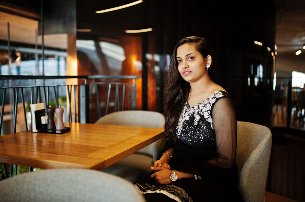 pretty indian girl in black saree dress posed at restaurant.