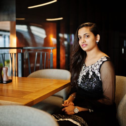 pretty indian girl in black saree dress posed at restaurant.